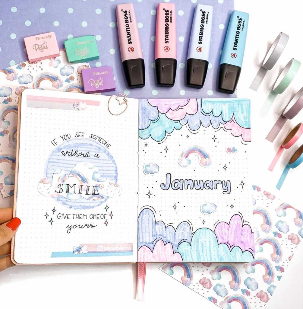 Colorful bullet journal with January page, rainbows, clouds, pastel highlighters, and decorative tape. Perfect for inspiration.