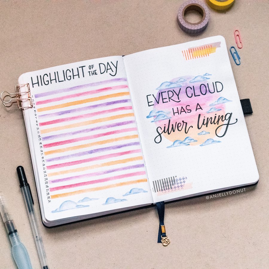 Open journal with colorful daily highlights and Every cloud has a silver lining quote, surrounded by stationery.