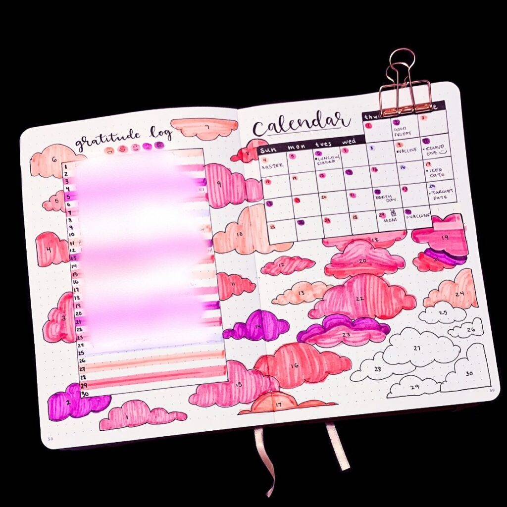 Colorful bullet journal with gratitude log and calendar, featuring pink and purple cloud illustrations.