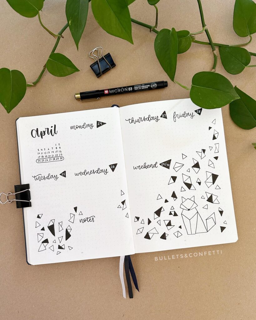 Open bullet journal for April with doodles and notes, surrounded by leaves. Pen and clips nearby.