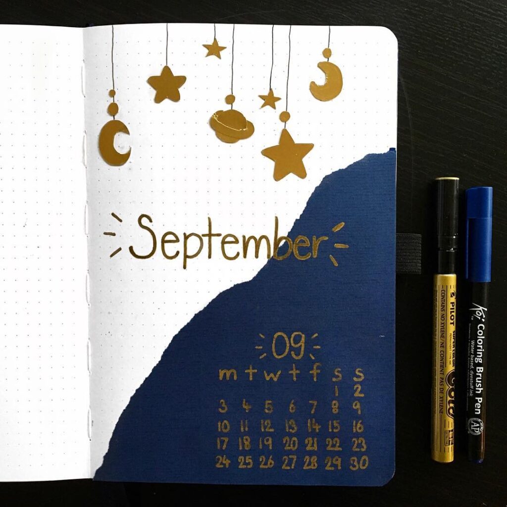 September bullet journal page with stars and moons, featuring a monthly calendar and pens on a dark background.