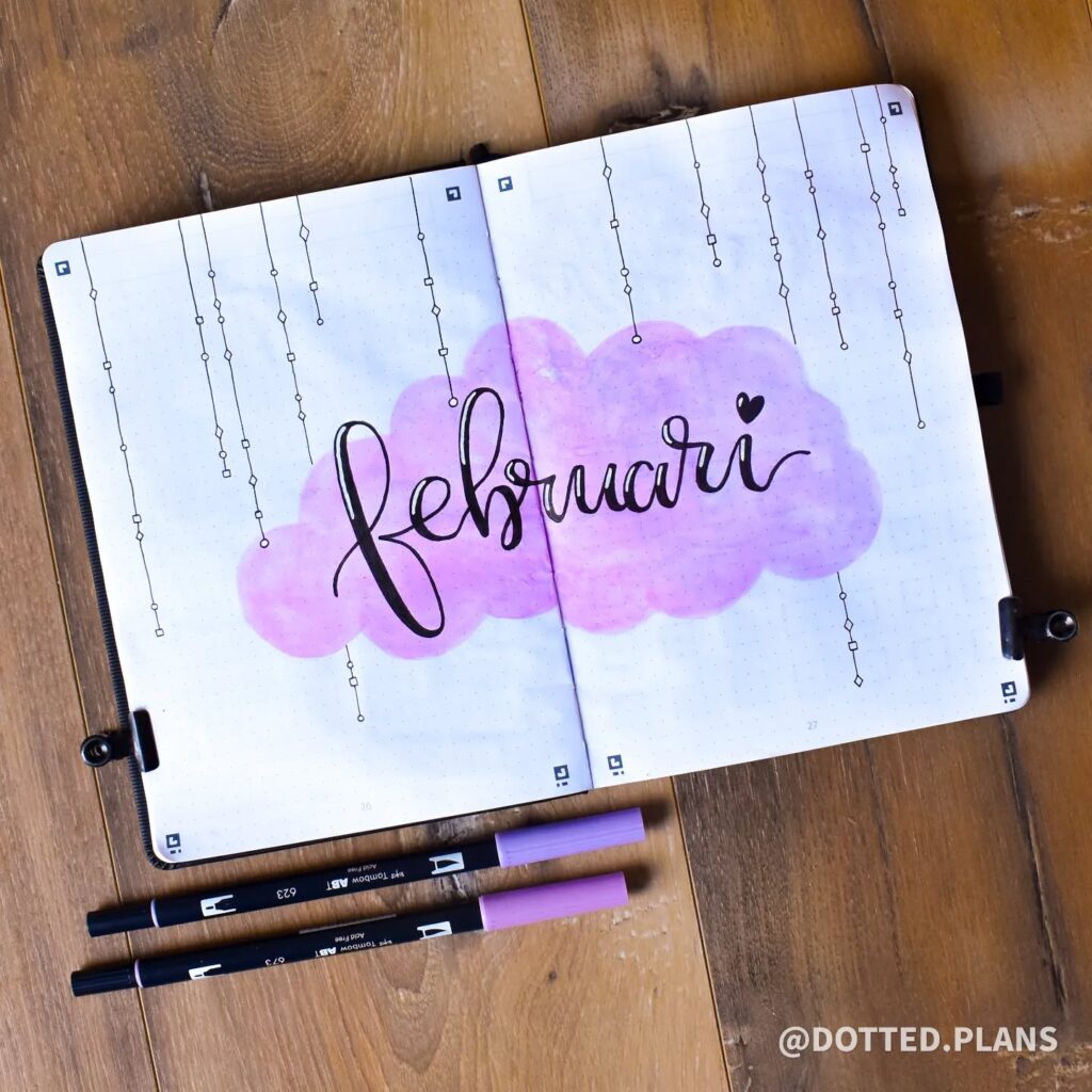 Bullet journal open to a February theme page with purple accents and calligraphy.
