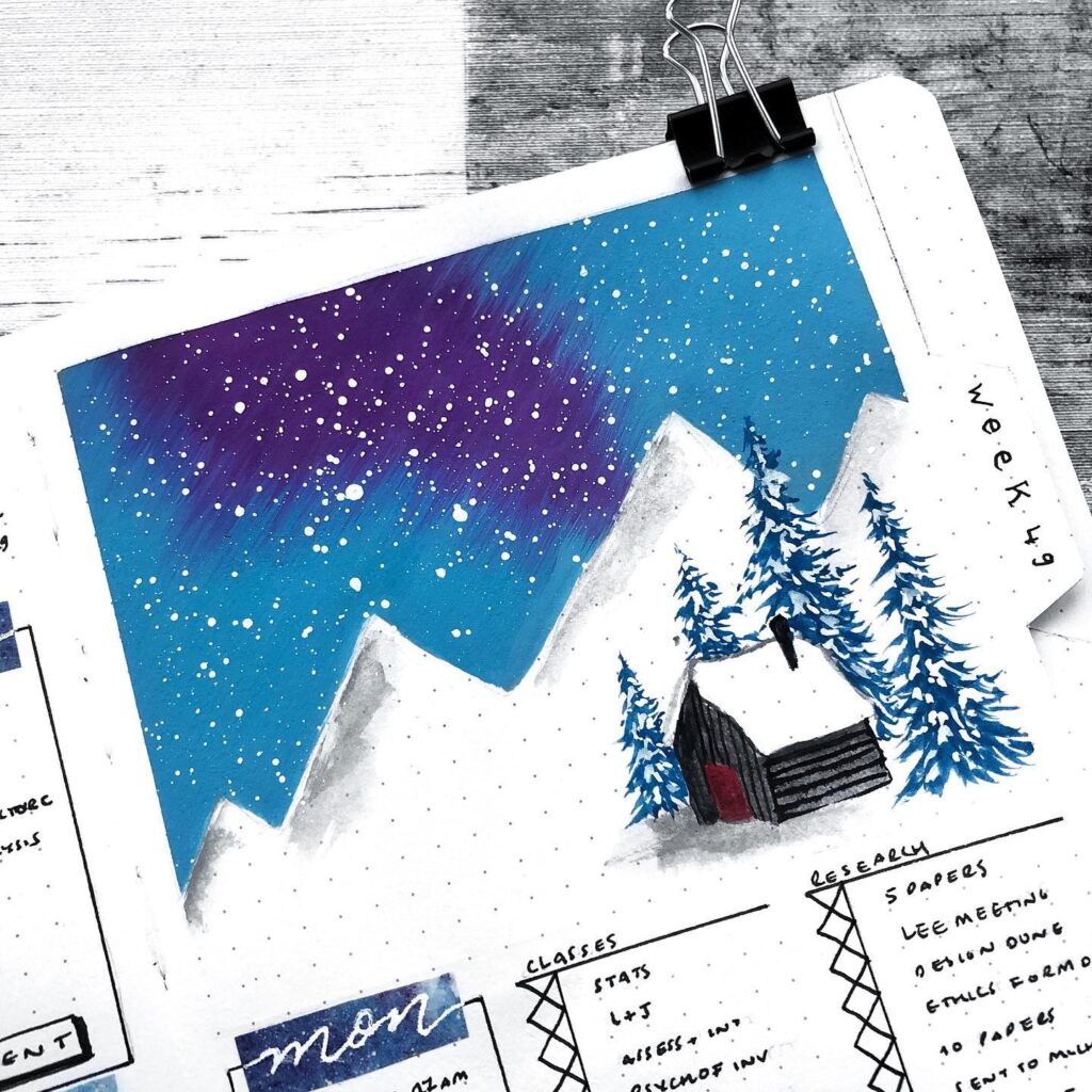 Winter bullet journal with a snowy mountain scene, starry sky, and pine trees, week 49 planning visible.