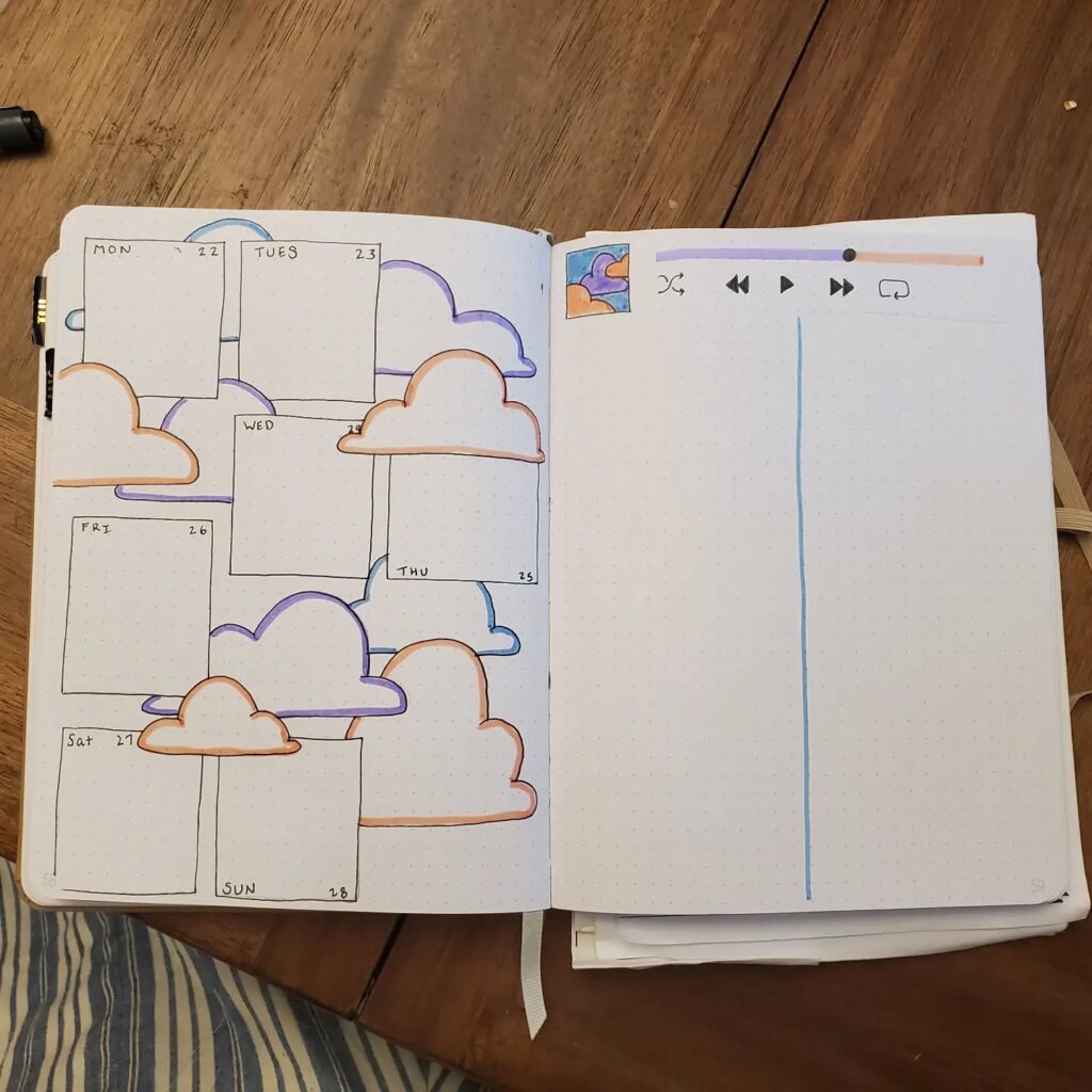 Bullet journal weekly planner with cloud-themed design on a wooden table.