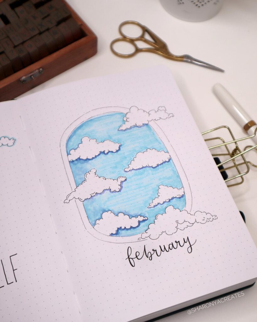 Bullet journal page with February's cloud-themed doodle art in a window frame, featuring scissors and a pen nearby.