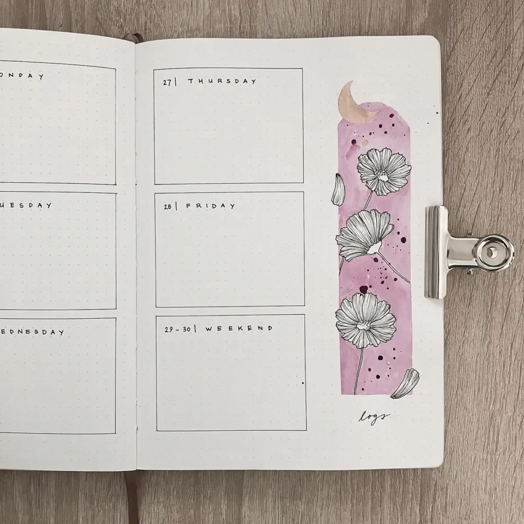Open bullet journal with a weekly planner layout and floral doodles on a wooden table background.