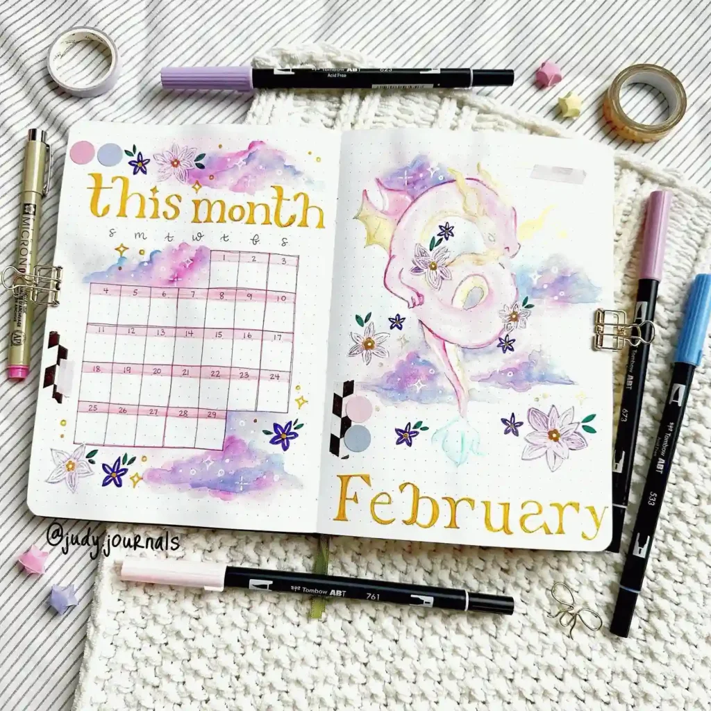 February bullet journal spread with dragon illustration, colorful pens, and floral designs. Creative planner setup.