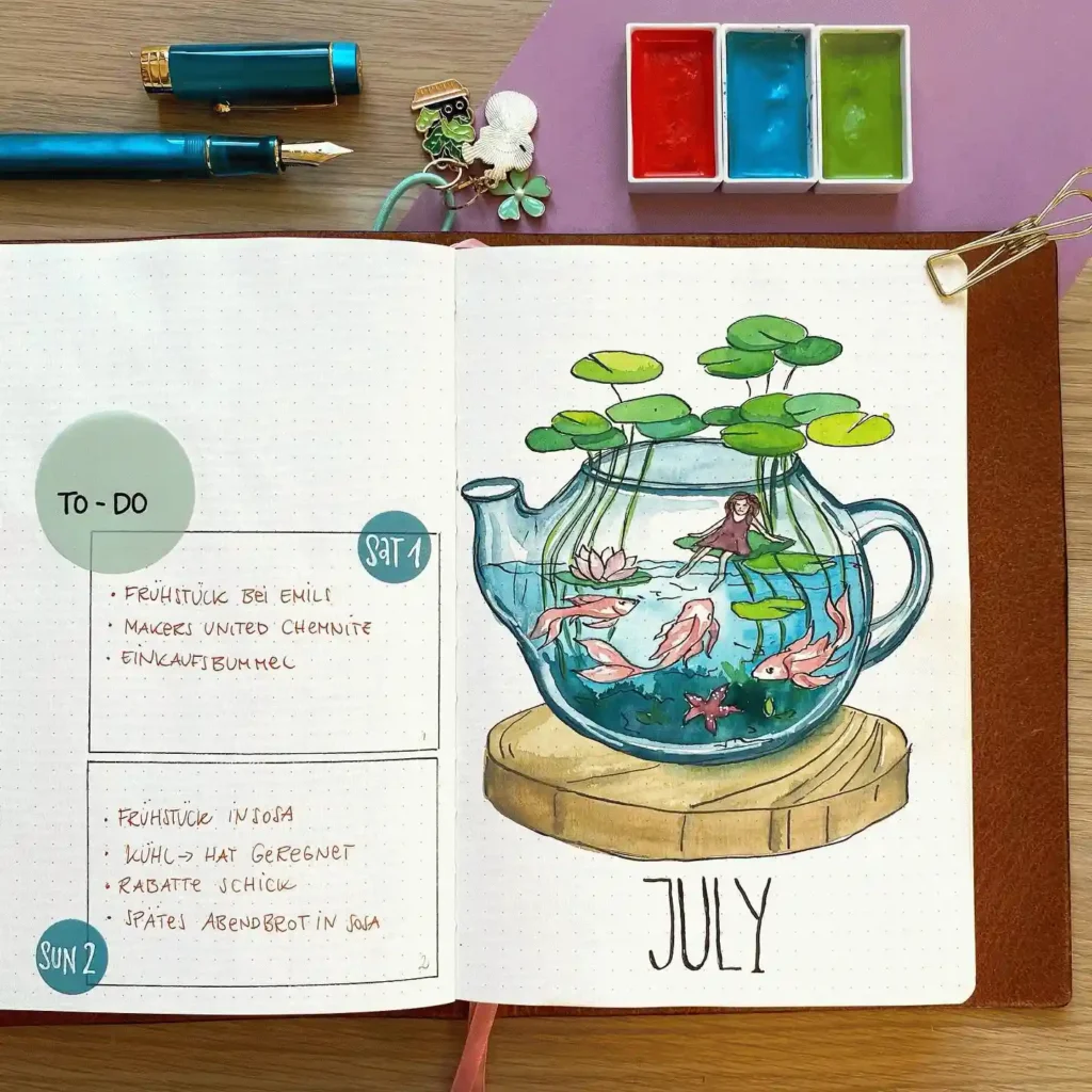 July bullet journal spread with colorful teapot illustration, fish, and water plants. Creative and artistic notebook layout.