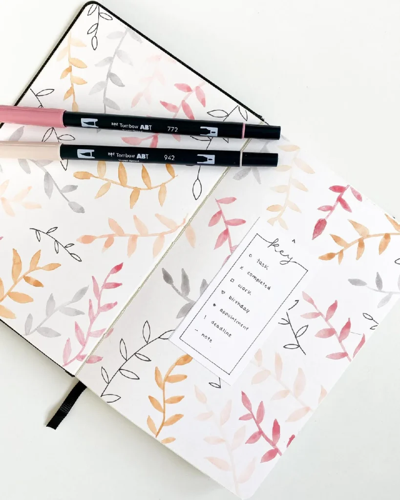 Elegant bullet journal page with watercolor leaves and Tombow markers, featuring a task list and key design for organization.