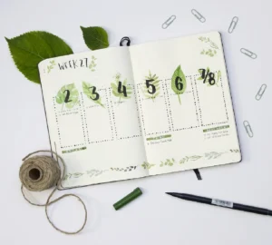 Weekly planner spread for Week 27, featuring green leaves, handwritten numbers, stationery, and nature-inspired design elements.