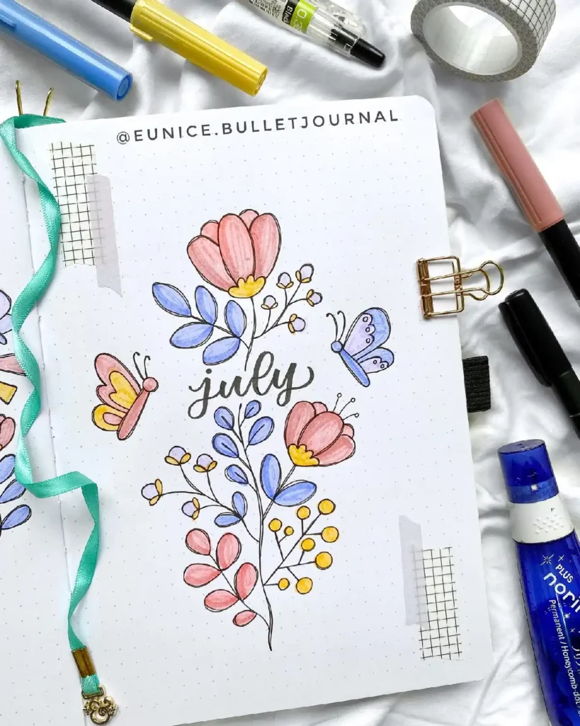 Colorful bullet journal page for July, featuring floral doodles and butterflies, surrounded by stationery supplies.