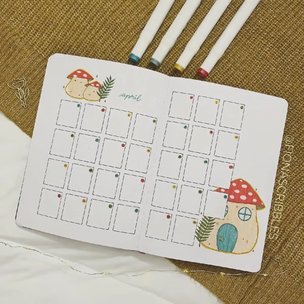Bullet journal layout for April, featuring a cute mushroom house and colorful markers on a textured background.