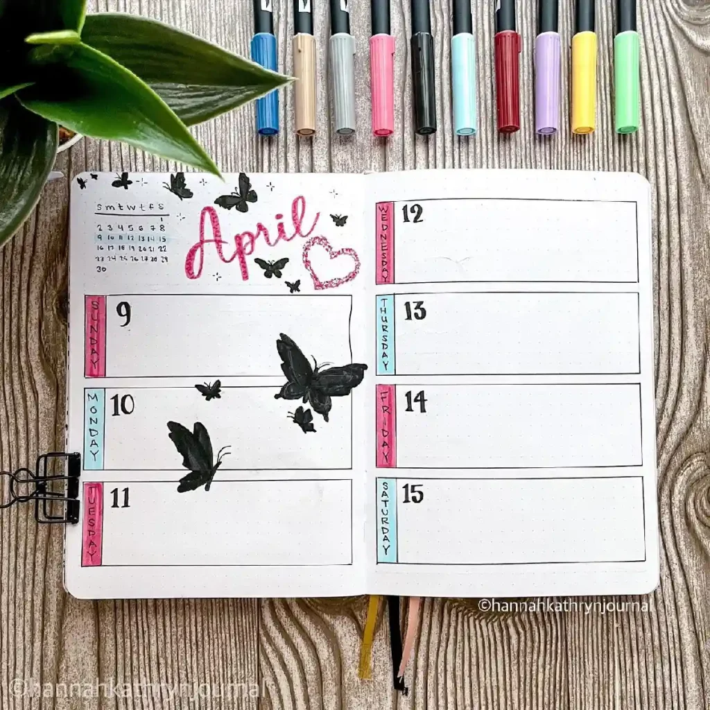 Colorful bullet journal spread for April, featuring butterflies, weekly layout, and vibrant markers on a wooden surface.