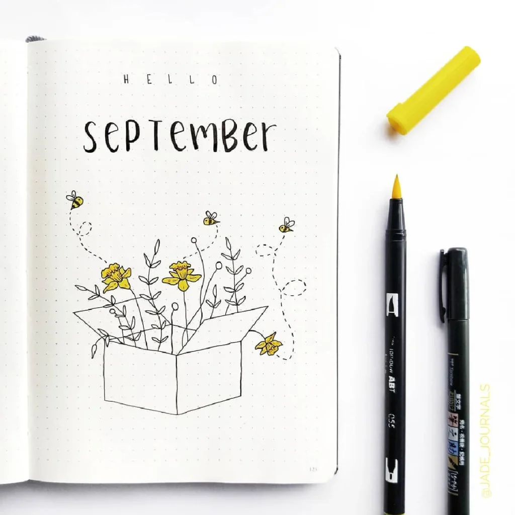 September bullet journal page with hand-drawn flowers and bees, featuring black and yellow art supplies.