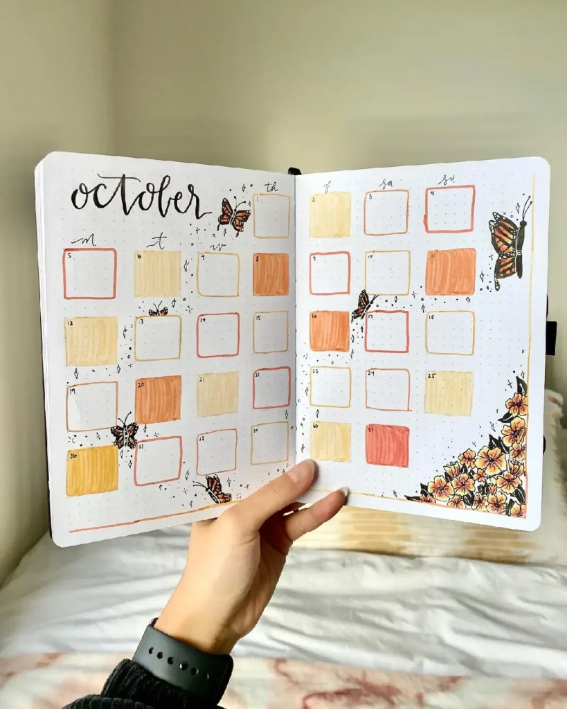 Hand-drawn October calendar spread with pastel colors, butterflies, and floral accents in a bullet journal.