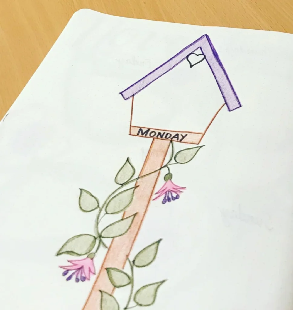 Illustration of a colorful birdhouse labeled 'Monday' surrounded by flowers and vines in a bullet journal.