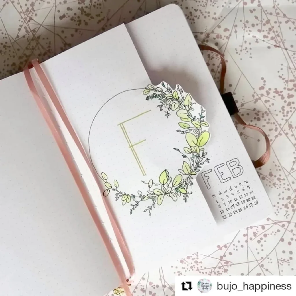 Bullet journal spread for February with floral designs, month calendar, and initial 'F' in a decorative wreath.