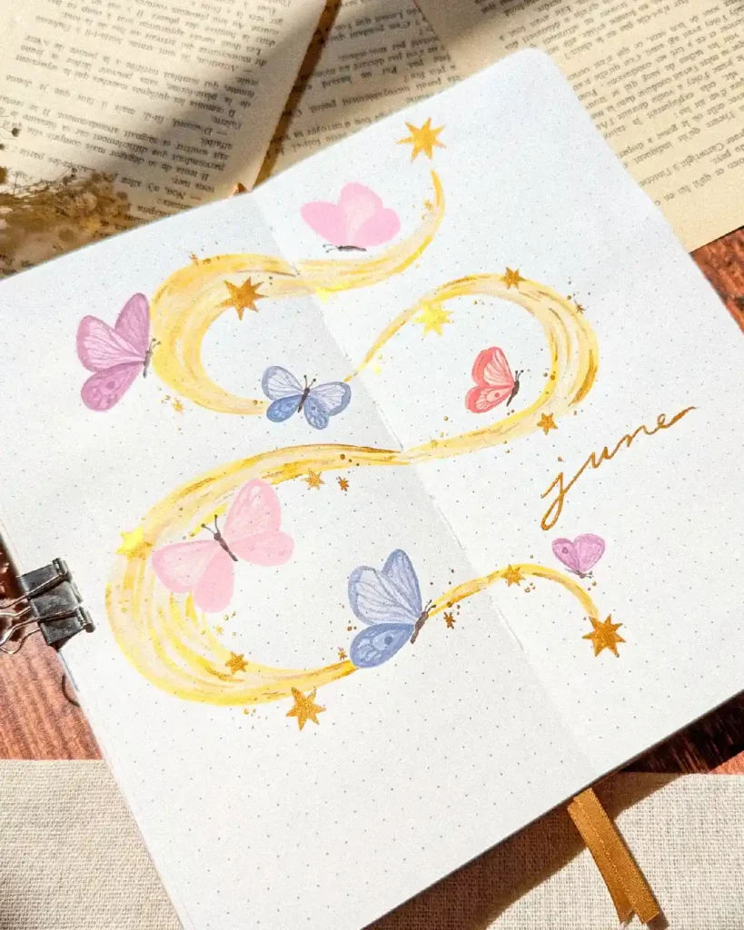 Colorful butterflies and stars adorn a June bullet journal page, showcasing vibrant illustrations on dotted paper.
