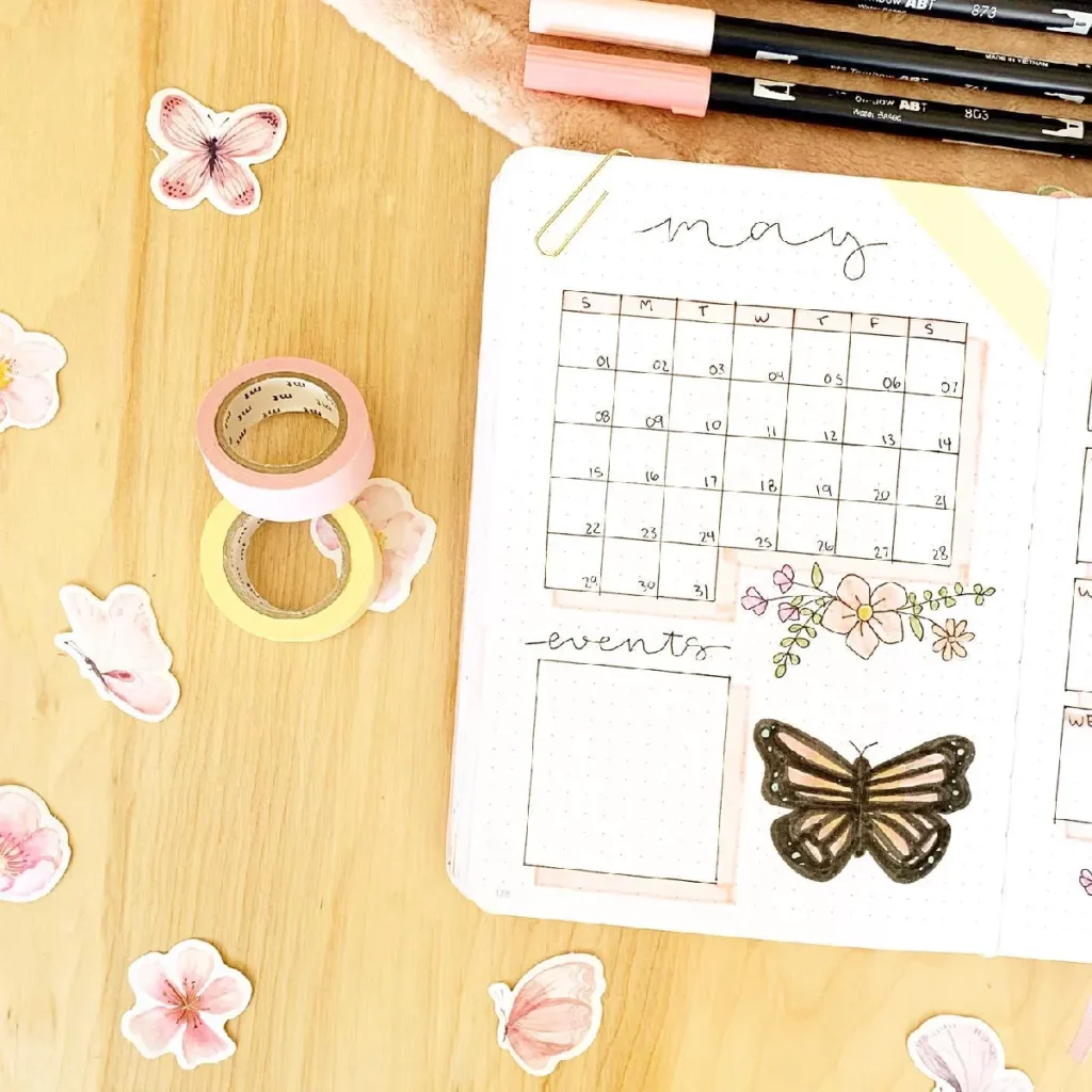 Alt text: Colorful bullet journal page for May with a calendar, floral stickers, and decorative washi tape.
