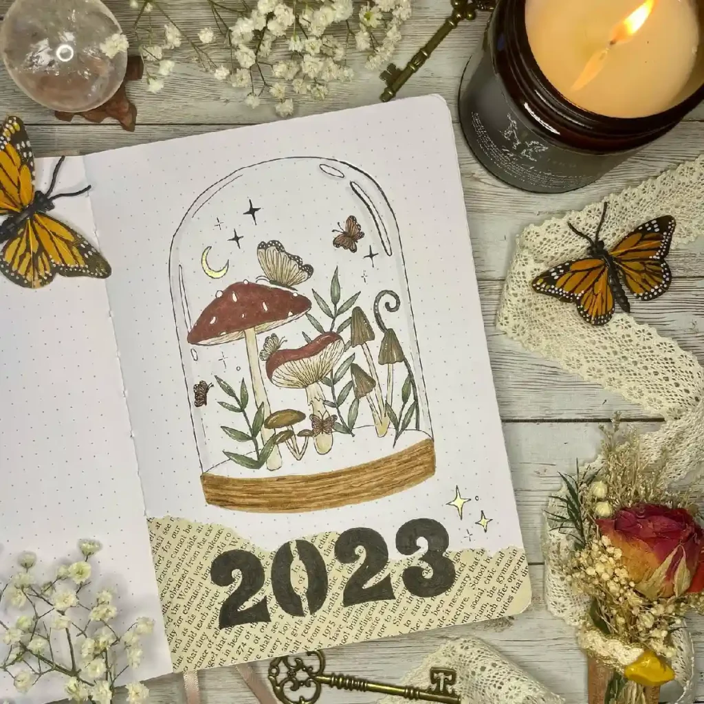Artistic journaling spread featuring a glass dome with mushrooms, butterflies, and 2023, surrounded by decorative elements.