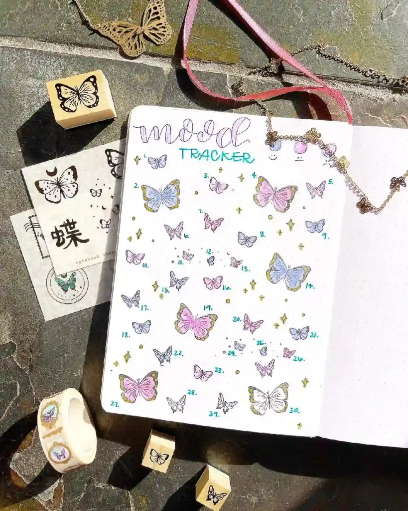 Colorful mood tracker with butterfly illustrations, decorative stamps, and journaling supplies on a textured surface.