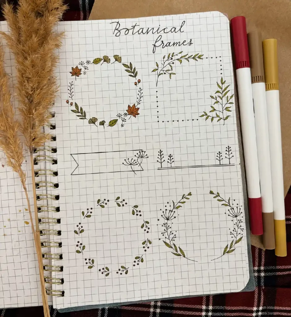 Hand-drawn botanical frames and sketches in a notebook, surrounded by art supplies and decorative grasses.