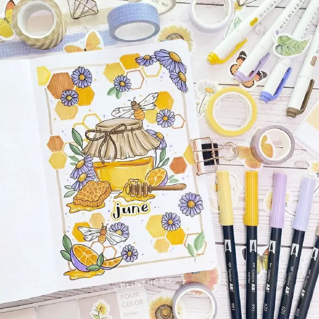 Colorful June bullet journal spread featuring honey, bees, flowers, and art supplies for a creative month ahead.