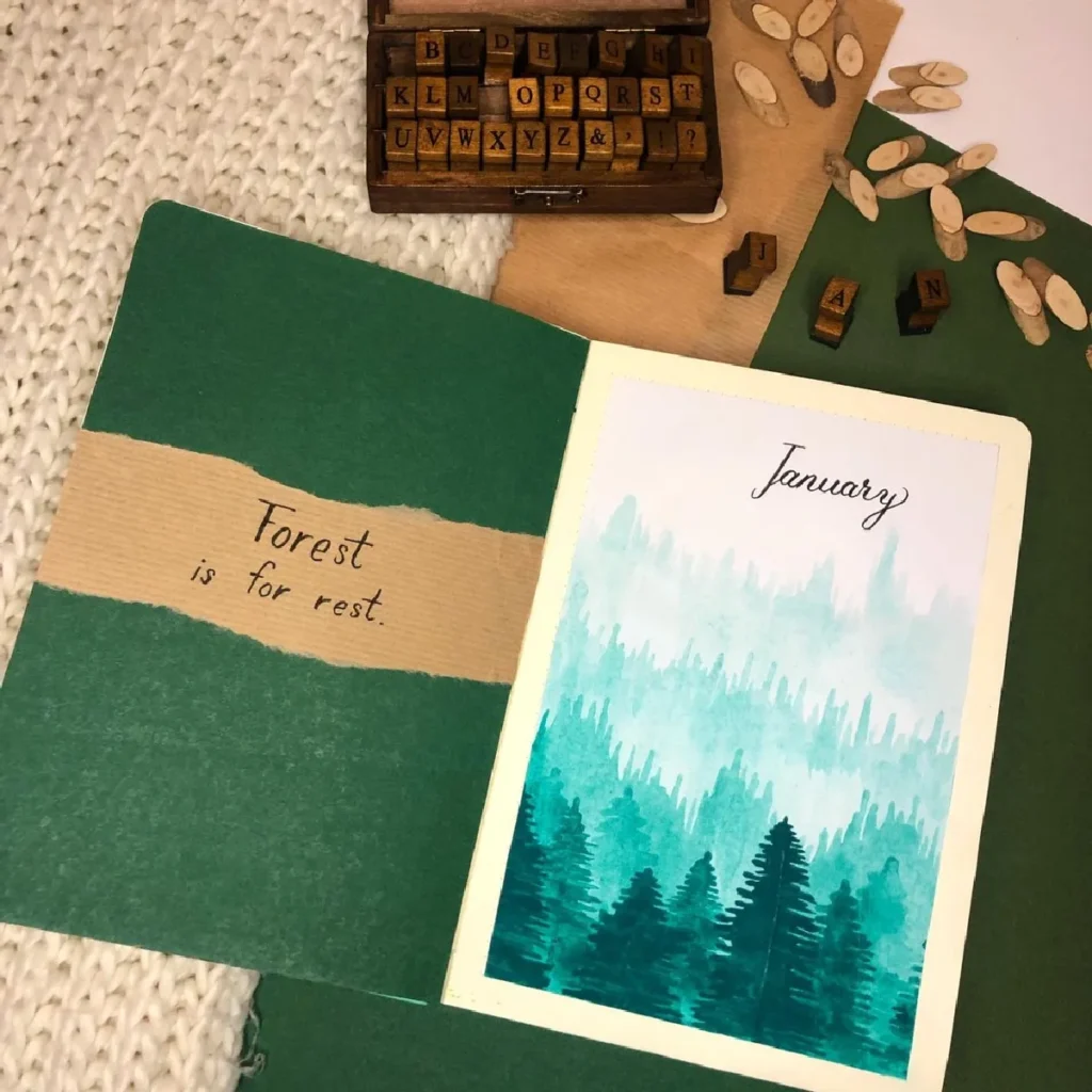Green notebook spread with Forest is for rest and a watercolor January illustration of trees. Vintage letter stamps nearby.