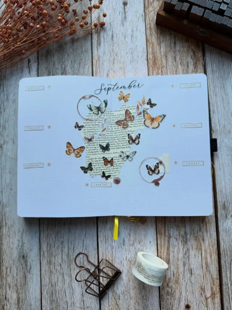 September bullet journal page decorated with colorful butterflies and a vintage text background on a wooden table.