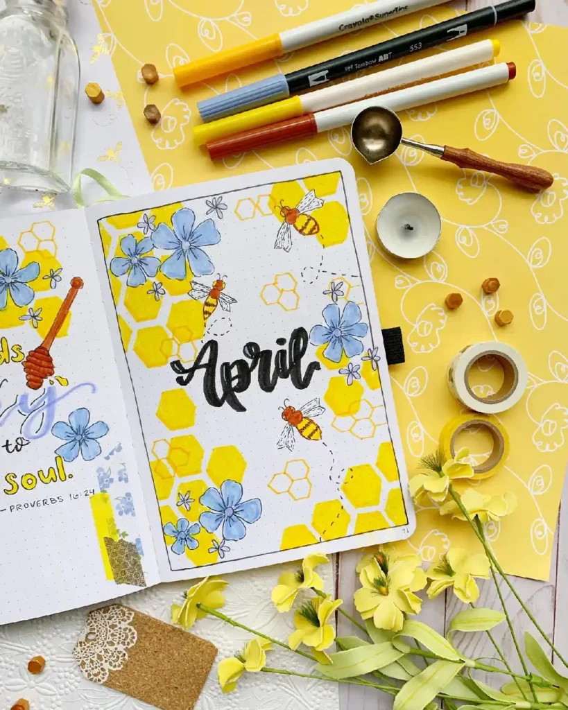 Colorful April bullet journal spread with flowers, bees, and honeycomb art, set against a vibrant yellow background.