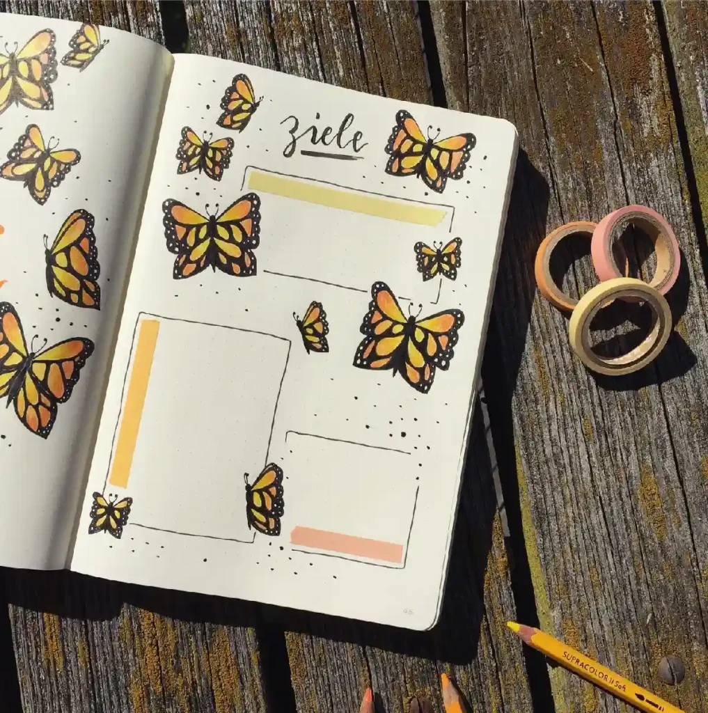 Colorful butterfly-themed bullet journal layout with washi tape and colored pencils on a wooden surface.